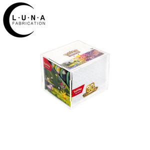 May include: A clear acrylic display case containing a Pokemon Trading Card Game 30th Celebration box. The box features colorful character illustrations, the Pokemon logo, and a 30th Celebration emblem. The Luna Fabrication logo is visible above.
