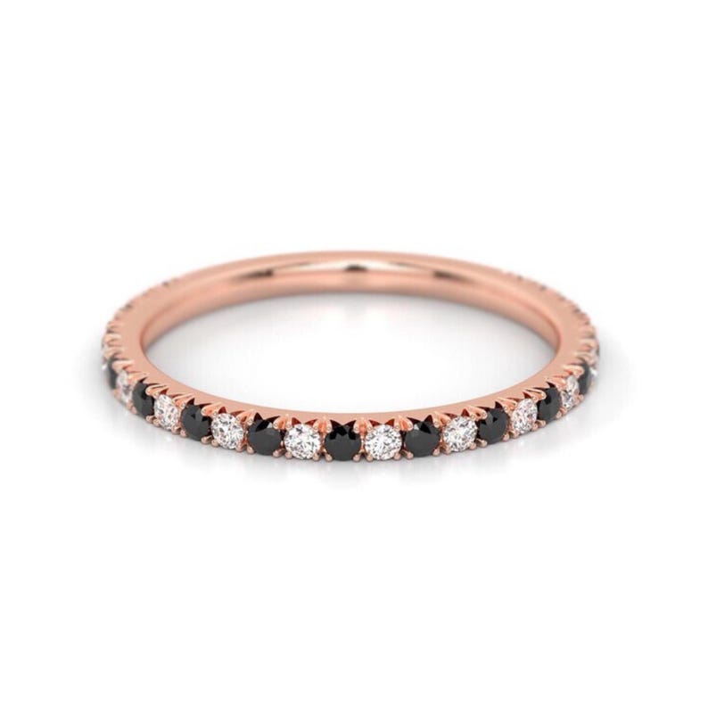 K&ouml;nnte beinhalten: Ein Ros&eacute;gold-Bandring mit einer Reihe abwechselnder schwarzer und wei&szlig;er Diamanten.