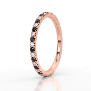 K&ouml;nnte beinhalten: Ein Ros&eacute;gold-Bandring mit einer Reihe abwechselnder schwarzer und wei&szlig;er Diamanten.