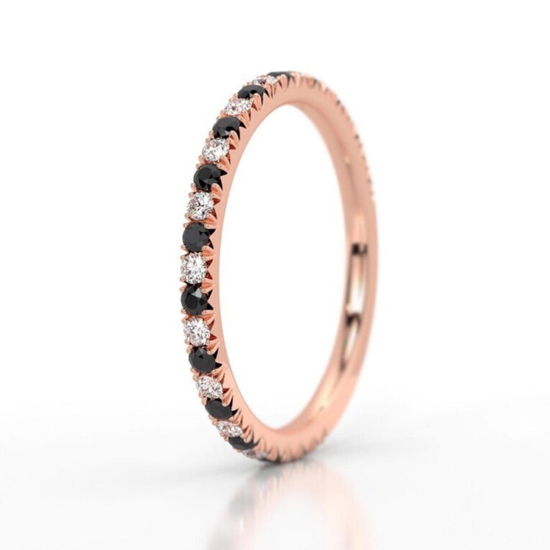 K&ouml;nnte beinhalten: Ein Ros&eacute;gold-Bandring mit einer Reihe abwechselnder schwarzer und wei&szlig;er Diamanten.
