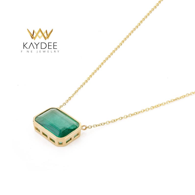 Op de afbeelding: Een gouden ketting met een rechthoekige, smaragdgroene edelsteen hanger. De hanger is gezet in een gouden bezel met een fijne ketting. De ketting is van de "KAYDEE FINE JEWELRY" collectie.