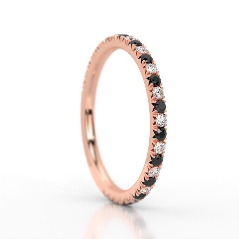 K&ouml;nnte beinhalten: Ein Ros&eacute;gold-Bandring mit abwechselnd schwarzen und wei&szlig;en Diamanten.
