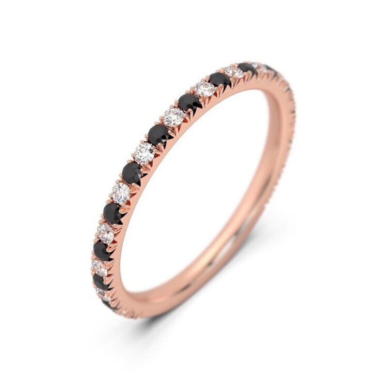 K&ouml;nnte beinhalten: Ein Ros&eacute;gold-Bandring mit abwechselnd schwarzen und wei&szlig;en Diamanten.