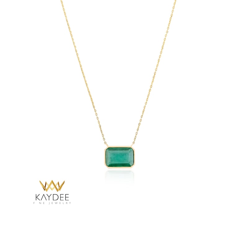 Op de afbeelding: Een gouden ketting met een rechthoekige smaragdgroene edelsteen hanger. De hanger is gezet in een gouden bezel en hangt aan een fijne gouden ketting. De ketting wordt gepresenteerd op een witte achtergrond. Het merklogo "KAYDEE FINE JEWELRY" staat in de linker benedenhoek.