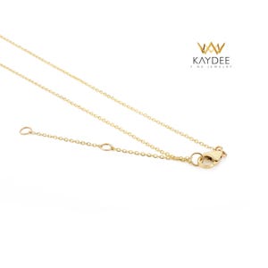 Op de afbeelding: Een delicate goudkleurige ketting met een fijne ketting en een karabijnsluiting. De ketting wordt getoond tegen een witte achtergrond. De merknaam "KAYDEE FINE JEWELRY" is rechtsboven zichtbaar.
