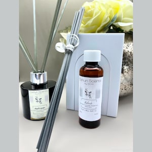 Può includere: Una bottiglia diffusore nera con canne grigie e una bottiglia di olio essenziale più piccola abbinata. Entrambe le bottiglie hanno un'etichetta bianca con il testo "Oshun Scents by SoW" e "Refresh Cucumber & Peppermint Watermelon Reed Diffuser Oil".