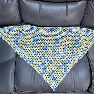 May include: A triangular crocheted shawl in white, blue, and yellow.