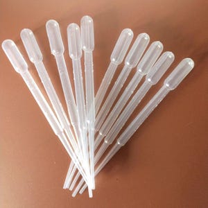 Puede incluir: Un conjunto de diez pipetas de transferencia de plástico transparente y flexible dispuestas en forma de abanico. Cada pipeta presenta un tallo largo y delgado y una sección superior bulbosa para succión, hecha de una sola pieza.