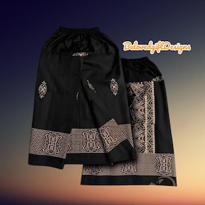 以下が含まれることがあります： 金色の模様が施された黒いスカートが2枚。スカートはゴムウエストで、幅広の装飾的なヘムが施されています。