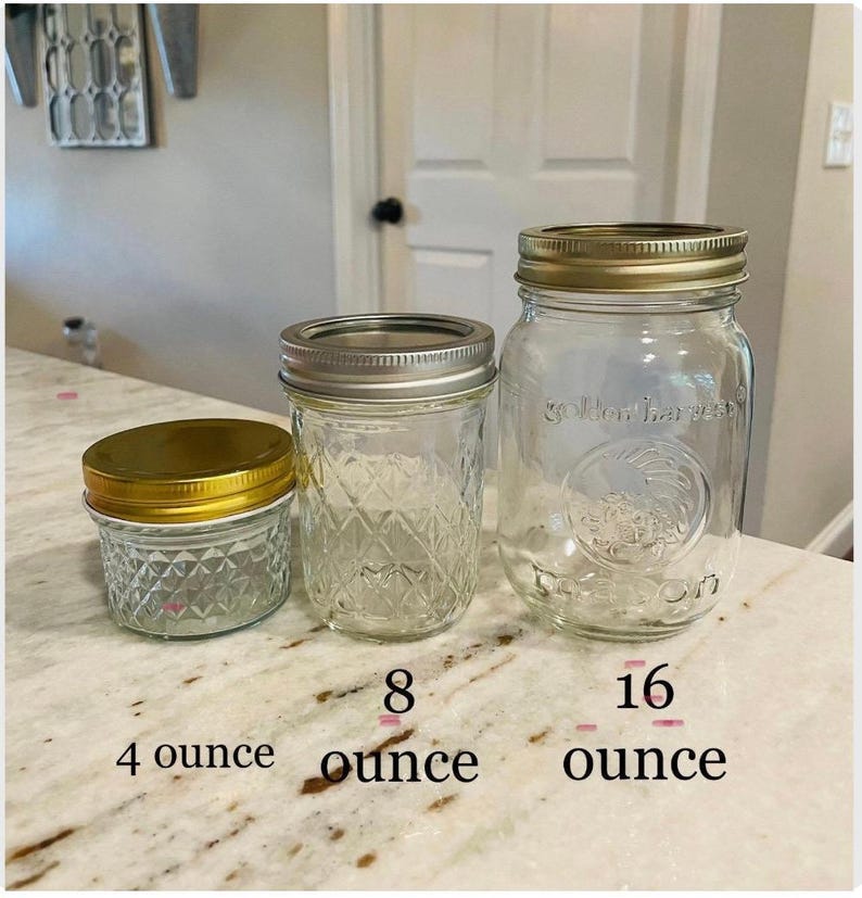 May include: Three glass jars with gold lids, labeled 4 ounce, 8 ounce, and 16 ounce. The jars are clear and have a textured surface.