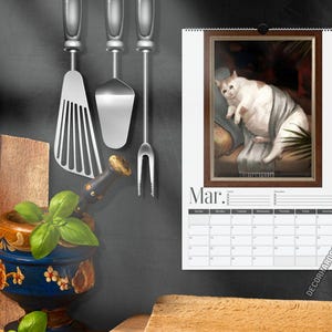 May include: A wall calendar for the month of March featuring a framed illustration of a white and brown cat resting on a sofa. The calendar includes a grid for dates and the text Mar. at the top. The design is displayed against a dark background.