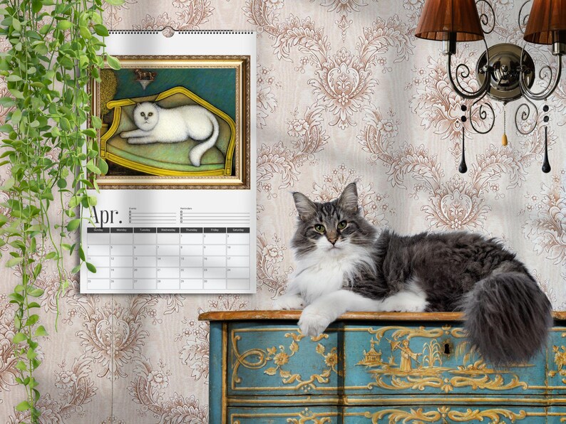May include: A wall calendar for April featuring a framed painting of a white cat resting on a yellow chair. A long-haired gray and white cat sits on a blue and gold painted wooden chest. The calendar has a white background with black text.