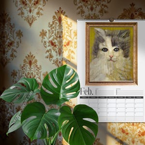 May include: A wall calendar for the month of February featuring a portrait of a fluffy cat with grey and white fur against a yellow background, enclosed in a gold-toned frame. The calendar includes a grid for dates and the text Feb. at the top.