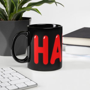 Könnte beinhalten: Schwarze Keramiktasse mit dem Wort "Happy" in roten Buchstaben.