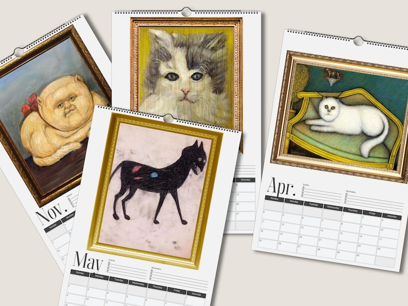 May include: A wall calendar featuring four pages with cat illustrations in gold frames. The pages show months labeled Nov., May, and Apr. with grid layouts. The cat art includes a fluffy orange cat, a grey and white cat, a black cat, and a white cat.