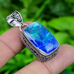 May include: A silver pendant with a blue and green opal gemstone set in a filigree design.