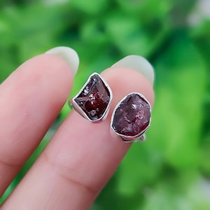 May include: A silver ring with two red garnet stones. The stones are raw and have a natural, irregular shape.