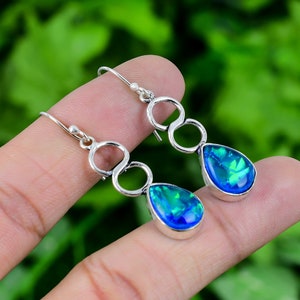 May include: A pair of silver dangle earrings with blue opal teardrop stones. The earrings feature a delicate infinity symbol design.