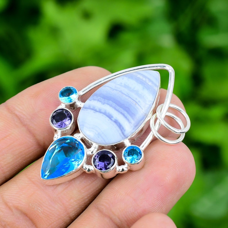 May include: A silver pendant featuring a blue agate gemstone surrounded by smaller blue and purple gemstones.