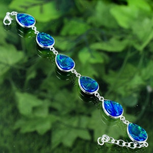 May include: A silver bracelet with a chain and five teardrop-shaped blue opal stones.
