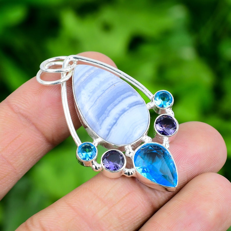 May include: A silver pendant featuring a blue agate gemstone, surrounded by smaller blue and purple gemstones.