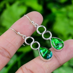 May include: A pair of silver dangle earrings with green opal teardrop stones. The earrings feature three interconnected circles.