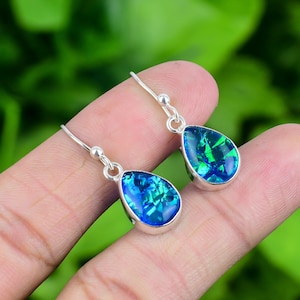 May include: A pair of silver teardrop earrings with blue opal stones. The earrings have a simple design and are perfect for everyday wear.
