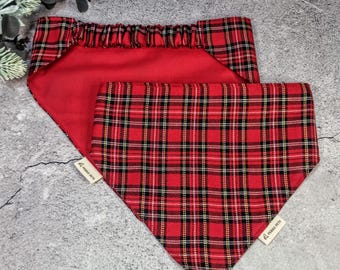 May include: Two red plaid dog bandanas. One bandana is a triangle shape with a red plaid pattern, and the other is a red rectangle with elastic. Both bandanas have a small white tag with the text "PERKY PETS".