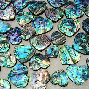 Könnte beinhalten: Eine Sammlung von herzförmigen Abalone-Muscheln mit schillernder Oberfläche. Die Muscheln zeigen eine Mischung aus Blau-, Grün- und Lilatönen mit einzigartigen Mustern. Geeignet für Schmuckherstellung oder Bastelprojekte.