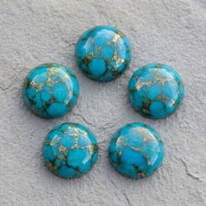 May include: Five round, polished cabochons featuring a vibrant turquoise blue color with intricate, branching gold-colored metallic veining throughout each stone. The stones are arranged in a circular pattern, showcasing a smooth, domed surface finish.