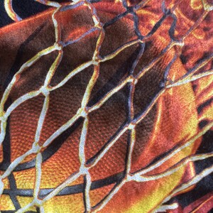 Puede incluir: Primer plano de una pelota de baloncesto con un esquema de color naranja y amarillo. La pelota de baloncesto est&aacute; cubierta con una red blanca.