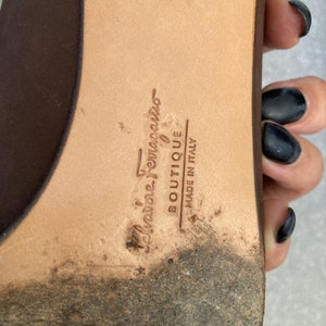 May include: Close-up of the brown leather sole of a shoe with the text "Salvatore Ferragamo Boutique Made in Italy" embossed on it.