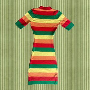 Puede incluir: Un vestido a rayas multicolor con mangas cortas. El vestido presenta bandas horizontales rojas, naranjas, amarillas y verdes. El vestido tiene cuello alto y una silueta ajustada.