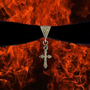 May include: A black velvet choker with a silver cross pendant and a decorative silver clasp. The background is a fiery orange and red.
