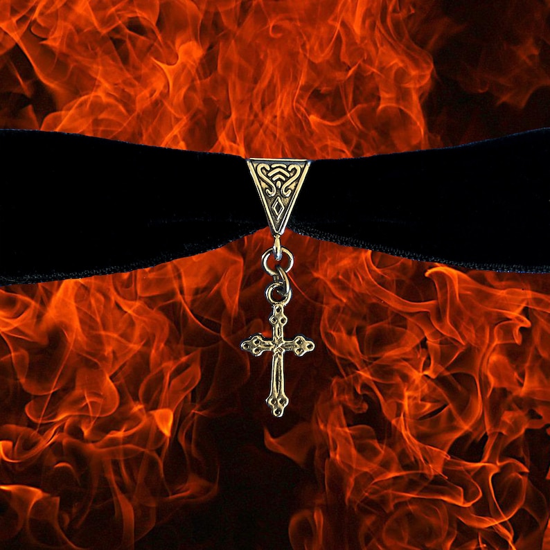 May include: A black velvet choker with a silver cross pendant and a decorative silver clasp. The background is a fiery orange and red.