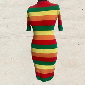 Puede incluir: Un vestido ajustado con cuello alto y mangas cortas. El vestido presenta rayas horizontales en rojo, naranja, amarillo, verde y un rojo m&aacute;s oscuro. El vestido se exhibe en un maniqu&iacute;.