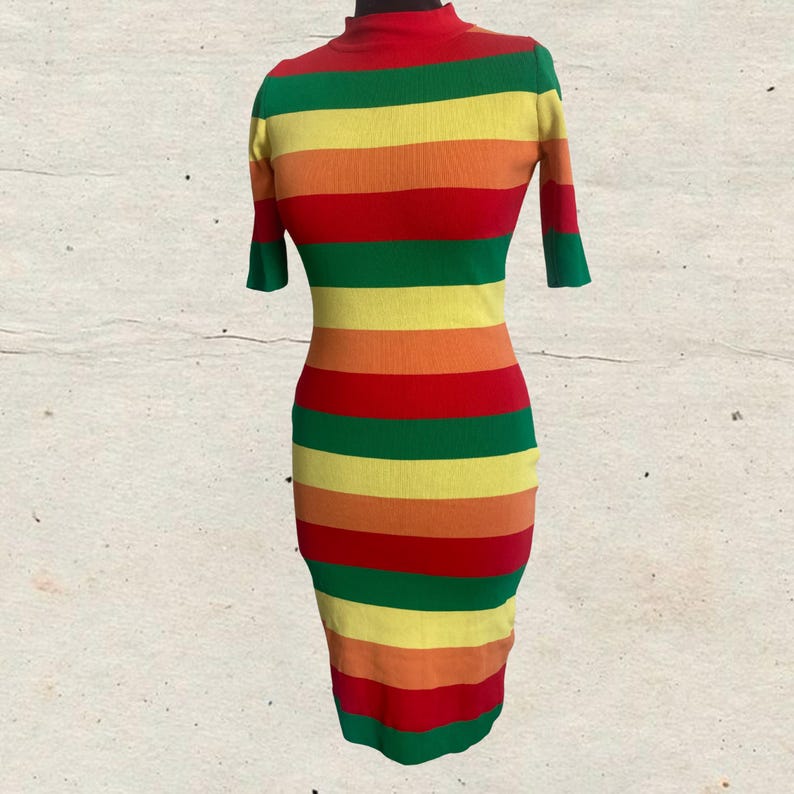 Puede incluir: Un vestido ajustado con cuello alto y mangas cortas. El vestido presenta rayas horizontales en rojo, naranja, amarillo, verde y un rojo m&aacute;s oscuro. El vestido se exhibe en un maniqu&iacute;.
