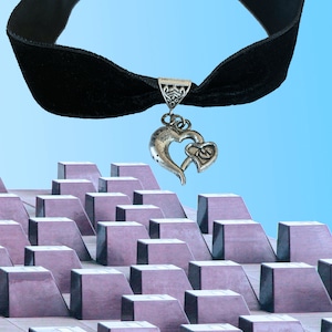 May include: A black velvet choker necklace with a silver heart pendant. The pendant features two intertwined hearts.