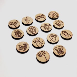 May include: Set of 14 wooden tokens with various symbols, including a deer, a hand, a shield, a paw print, a skull, a snake, a sword, a staff, a pair of glasses, a pentagram, and a bull's head.