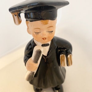 Figura de niño graduado con birrete y toga de cerámica vintage y diploma, ojos cerrados