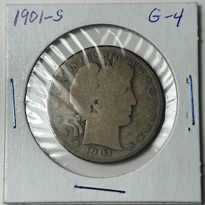 Puede incluir: Una moneda de plata de 1901-S, calificada G-4, está encerrada en un soporte protector. La moneda presenta un perfil de mujer y la inscripción "IN GOD WE TRUST". El año 1901 es visible en la moneda.