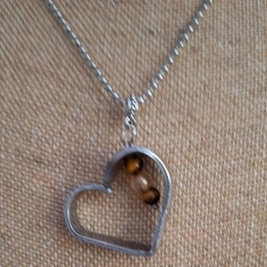 Unique recycled silverware made into floating heart. Stones inside of heart are semi precious tiger eye.
