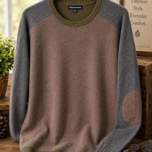 May include: A long-sleeve crewneck sweater featuring a brown torso, grey sleeves, and olive green ribbed trim at the collar and hem. The sweater includes a brown elbow patch on the right sleeve and a label inside the collar reading Tricots Raphael.