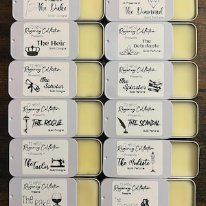 May include: Twelve rectangular silver metal tins containing solid cologne and solid perfume, arranged in two columns labeled His and Hers. Each tin features a white label with black text and icons, including titles like The Duke, The Diamond, and The Rake.