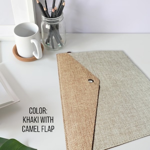 May include: Khaki envelope folder with a camel colored flap. The folder is made of a textured fabric material. The text "COLOR: KHAKI WITH CAMEL FLAP" is printed on the image.