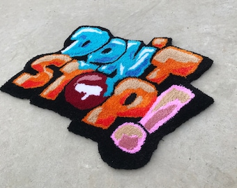 Puede incluir: Una alfombra colorida con las palabras "Don't Stop!" en estilo graffiti. La alfombra está hecha de hilo esponjoso y tiene un fondo negro.