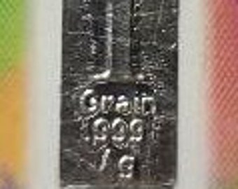 Può includere: Una barra d'argento con la scritta "1 Grain .999 Fine Silver" su di essa.