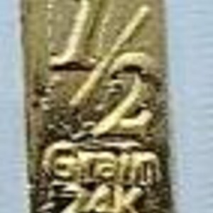 May include: A gold-colored metal charm with the number "12" and the words "Gram 24k" engraved on it.