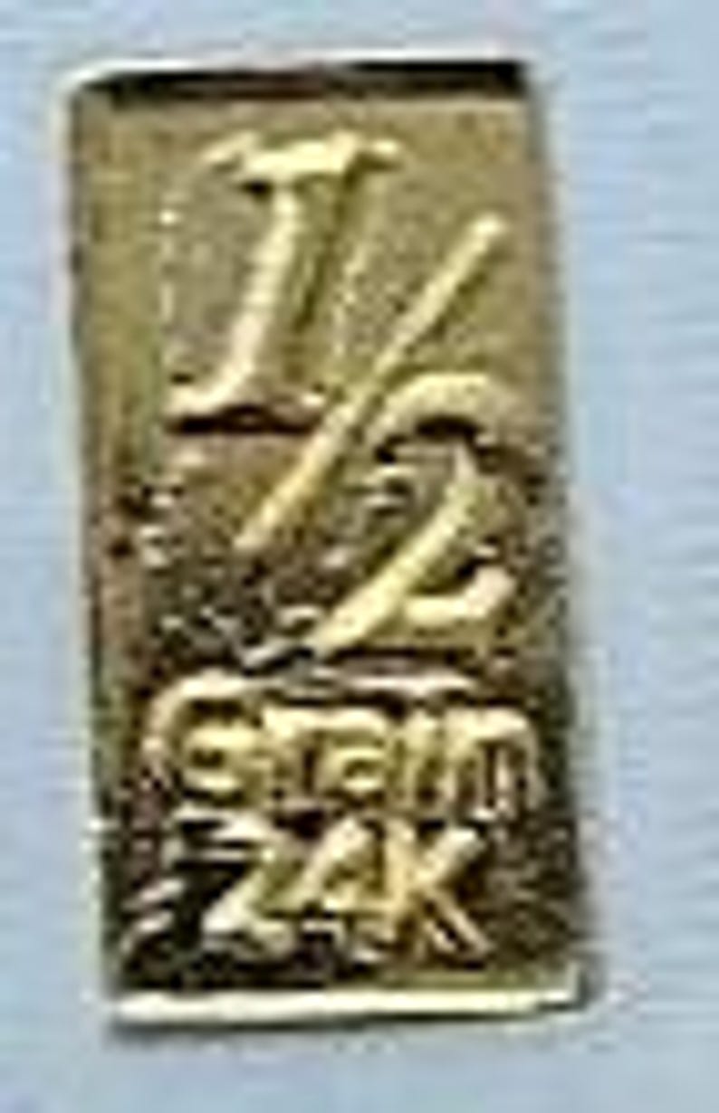 May include: A gold-colored metal charm with the number "12" and the words "Gram 24k" engraved on it.