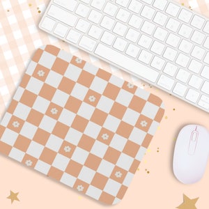 Peut inclure: Un tapis de souris &agrave; carreaux avec un motif brun clair et blanc et de petites fleurs blanches. Le tapis de souris est sur une surface rose avec des paillettes dor&eacute;es.